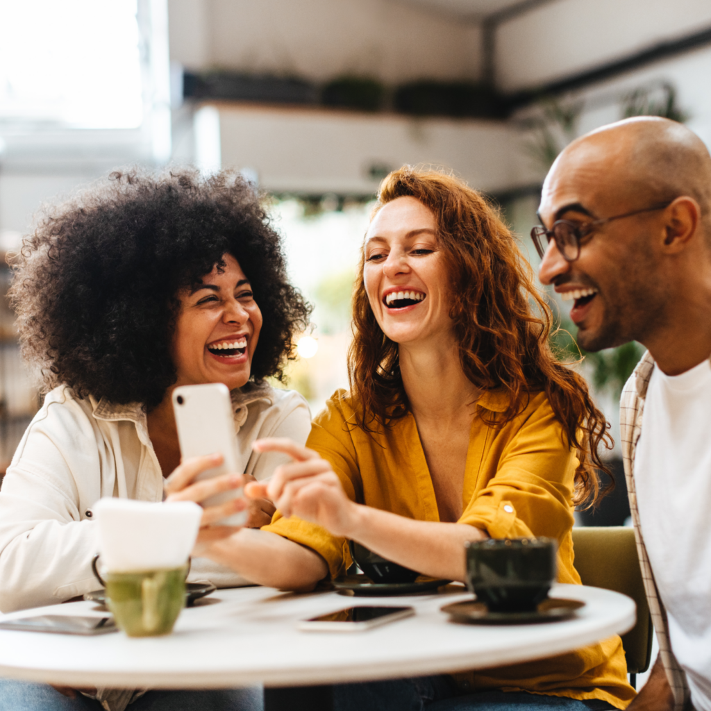 Three friends smiling at a phone together.