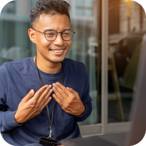 Young adult with glasses signing near a laptop.